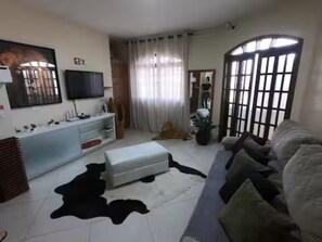 Una sala de estar con un sofá, un televisor, un armario blanco y una alfombra blanco y negro.