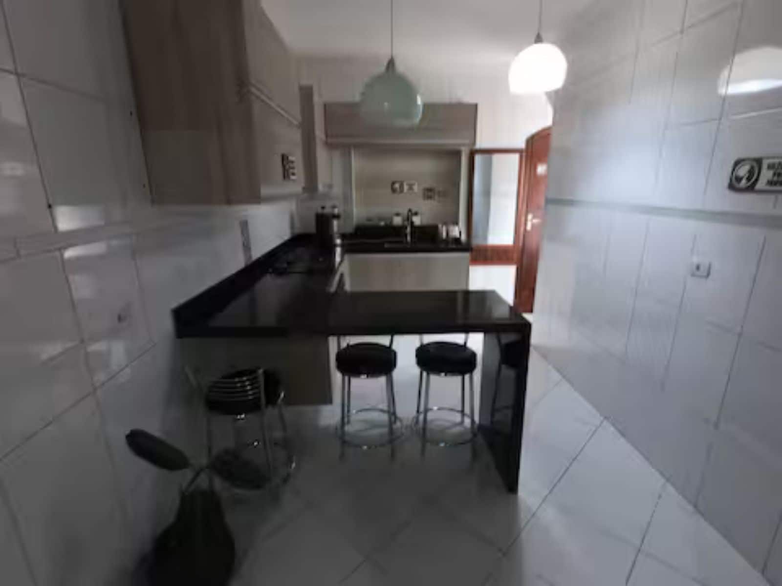 A modern kitchen with a central island, bar stools, and a hanging light fixture.