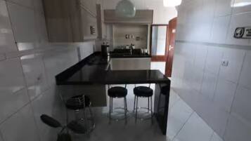 Une cuisine moderne dotée d’un îlot central, de tabourets de bar et d’un luminaire suspendu.