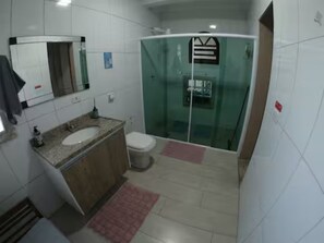 Casa de banho com lavatório, sanita e cabine de duche em vidro.