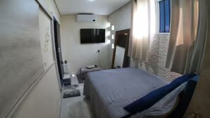 Une chambre à coucher avec un lit, une table de chevet, un miroir et une fenêtre.