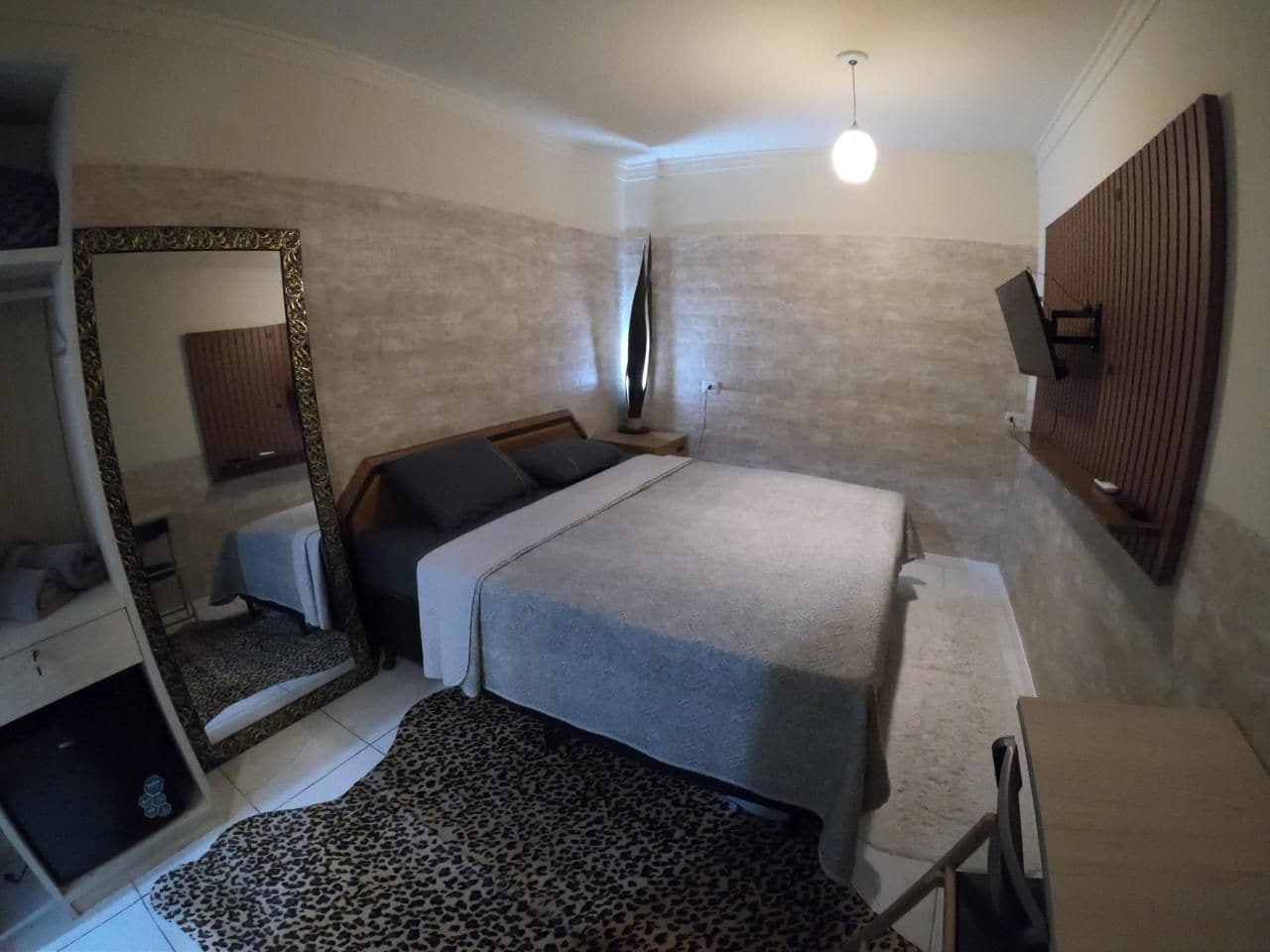 A bedroom with a bed, a mirror, a wardrobe, and a leopard print rug.