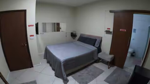 Une chambre à coucher comprenant un lit, des tables de chevet, une armoire et un miroir.