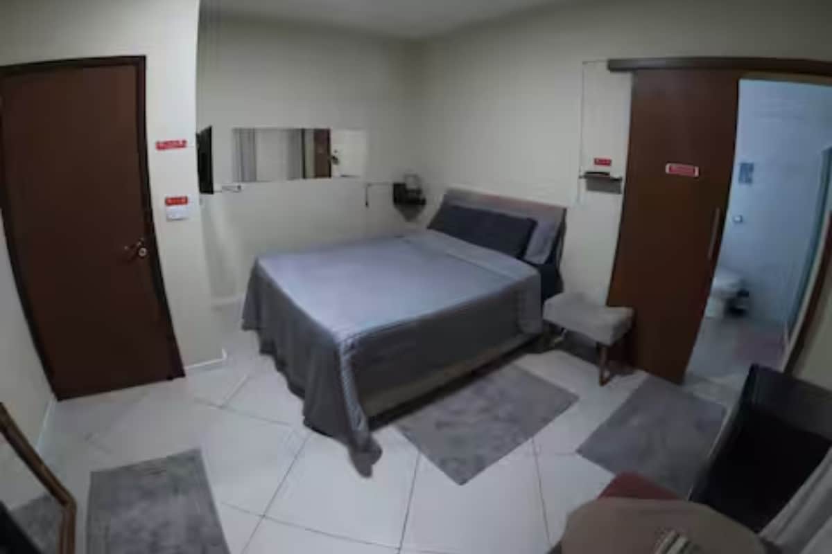 Quarto com cama, mesas de cabeceira, guarda-roupa e espelho.