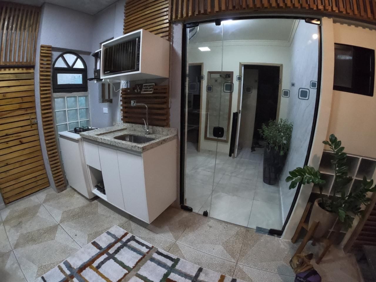 A kitchen with a built-in microwave, a sink, and a window with wooden shutters.
