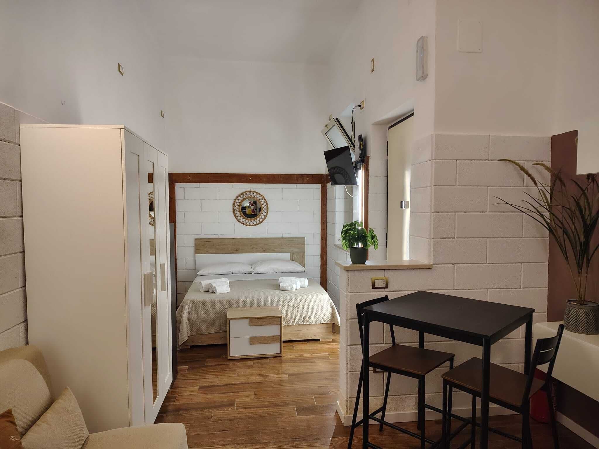 Een kleine hotelkamer met een bed, een tafeltje en een stoel.