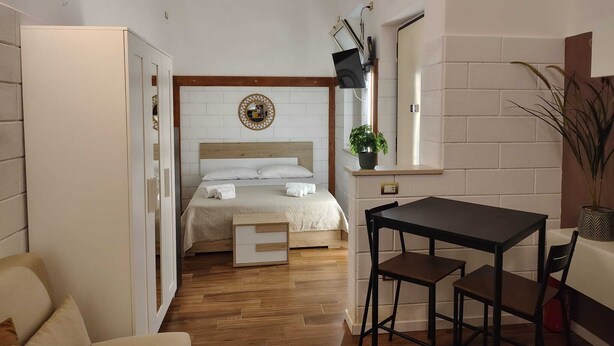 Una habitación de hotel pequeña con una cama, una mesita y una silla.
