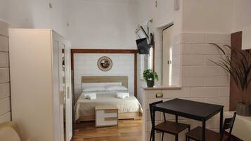 Een kleine hotelkamer met een bed, een tafeltje en een stoel.