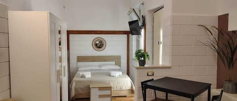 A compact hotel room with a bed, a small table, and a chair.