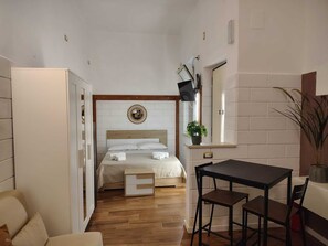Habitació d'hotel senzilla amb llit, taula petita i cadira.