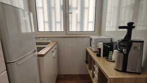 Cocina compacta equipada con refrigerador, microondas, tostadora y cafetera.