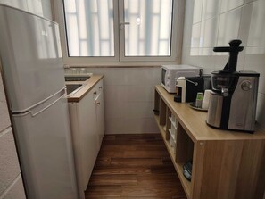 Une cuisine compacte équipée d’un réfrigérateur, d’un four à micro-ondes, d’un grille-pain et d’une machine à café.