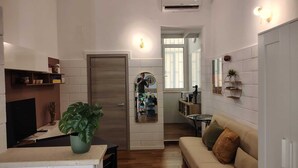 Un espacio habitable compacto con un sofá, una mesa de comedor, un televisor y una zona de cocina al fondo.