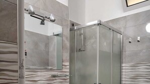 Un baño moderno con cabina de ducha de vidrio, tocador con espejo y retrete.