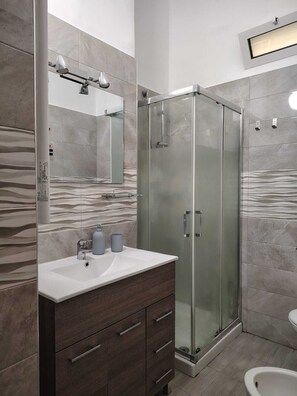 Une salle de bain moderne avec une douche à parois de verre, un meuble-lavabo avec un miroir et des toilettes.