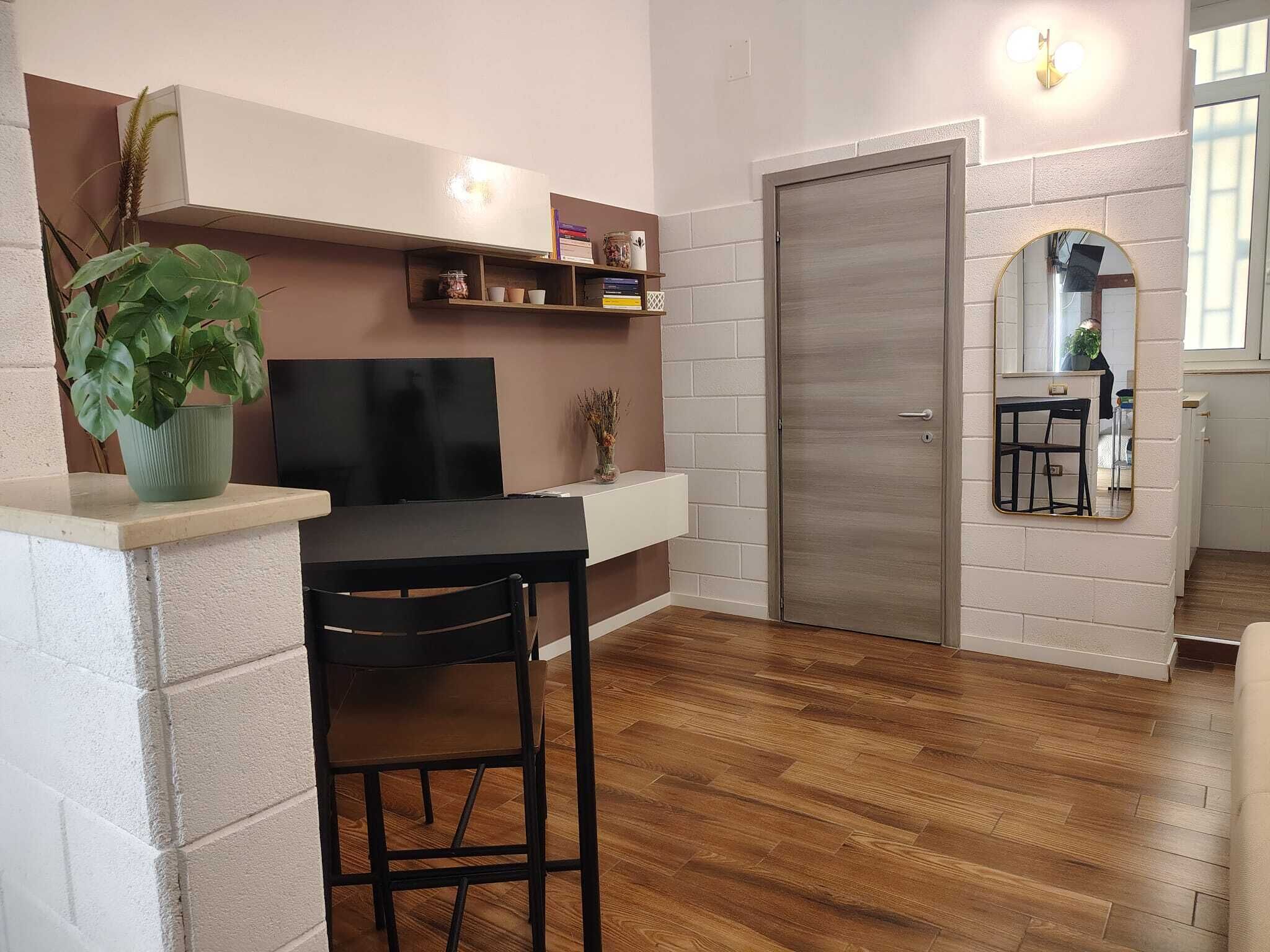 A modern kitchen with a built-in oven, a dining area with a table and chairs, and a large mirror above the sink.