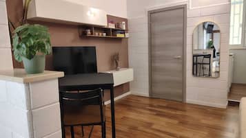 A modern kitchen with a built-in oven, a dining area with a table and chairs, and a large mirror above the sink.