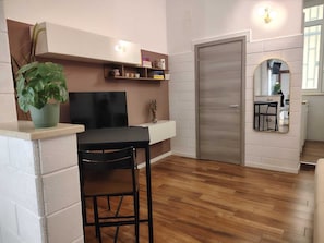 Una cuina moderna amb forn integrat, zona de menjador amb taula i caires, i un gran mirall sobre l'aigüera.