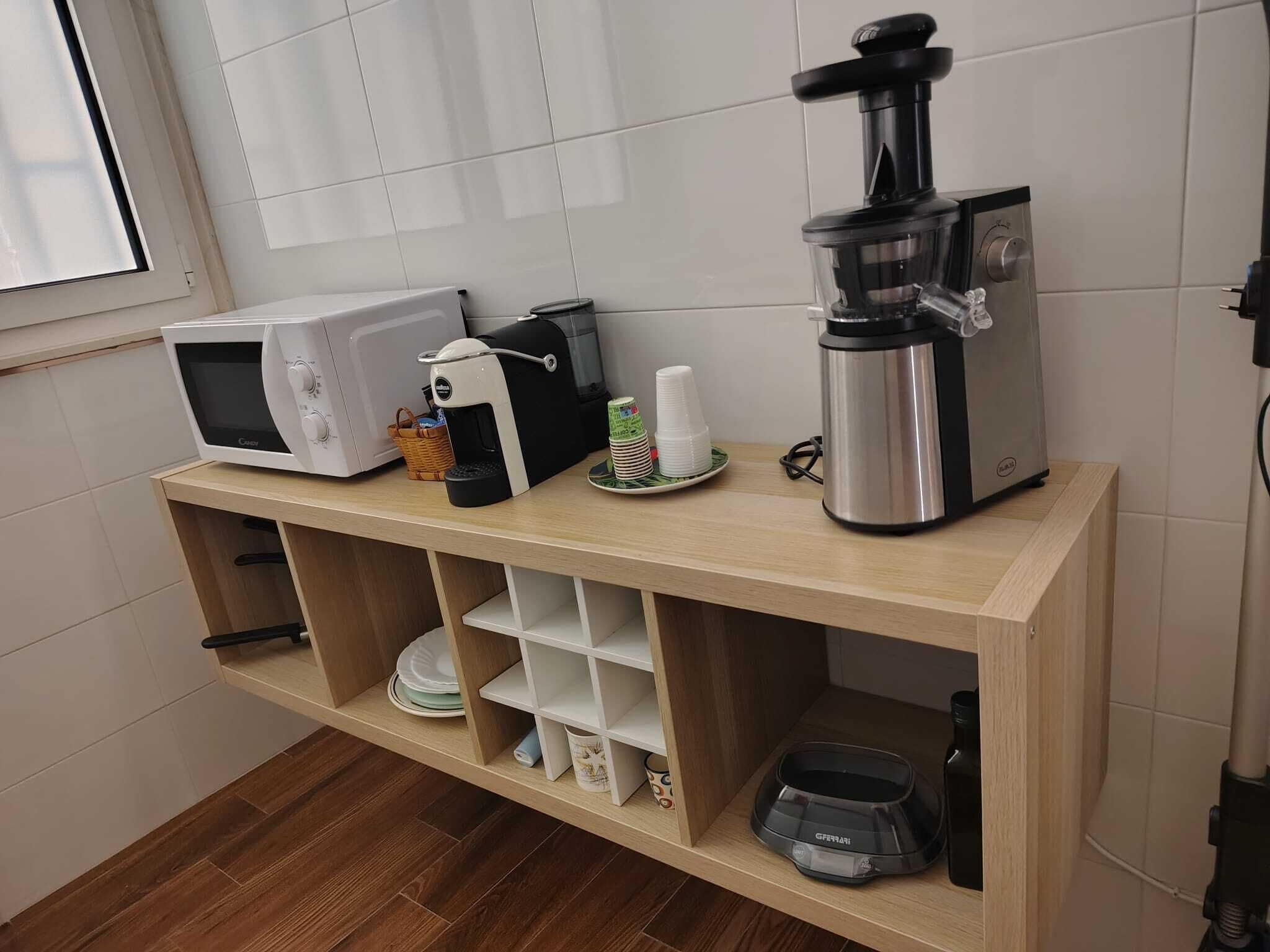 Une cuisine équipée d’un four à micro-ondes, d’une machine à café et d’une machine à expresso, le tout posé sur un plan de travail en bois.