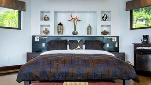 A bedroom with a large bed, a nightstand, a dresser, and decorative items on shelves. - Penthouse -Sky-High Privacy Above, Pool and Ocean Views. (Savegre de Aguirre, Puntarenas Province)