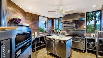 A commercial kitchen with a large oven, a stove, and a ventilation hood.