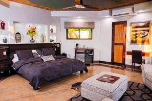 A modern bedroom with a large bed, bedside tables, a desk, and a chair.