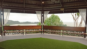 Uma área de estar coberta com um banco e vista para uma paisagem natural.