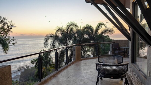A balcony with a view of the ocean, equipped with wicker chairs and a table. - Penthouse -Sky-High Privacy Above, Pool and Ocean Views. (Savegre de Aguirre, Puntarenas Province)