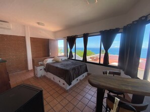 A bedroom with a bed, a desk, and a view of the ocean. - Montebello, apartments with spectacular ocean views. (Mazatlán)