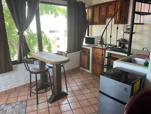 A compact kitchen with a dining table, chairs, a refrigerator, and a microwave. - Montebello, apartments with spectacular ocean views. (Mazatlán)