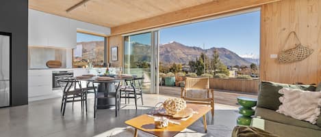 A modern interior with a dining area, kitchen, and a view of mountains.