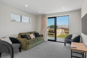 A modern living room with a green sofa, two armchairs, and a wooden coffee table. - The Cozy Koha - Taupo Holiday Home (Taupo)