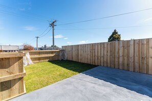 Ein Garten mit Holzzaun, Rasenfläche und Beton Terrasse.