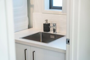 Eine moderne Küche mit einer Edelstahl-Spüle, einem Seifenspender und einem Fenster über der Spüle.