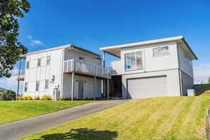 Une maison moderne à deux étages, dotée d’un garage, d’un porche couvert et d’un petit jardin à l’avant.