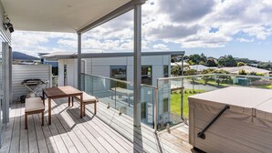 Eine moderne Außenterrasse mit Tisch und Stühlen, Glasgeländern und Blick auf die Nachbarschaft.