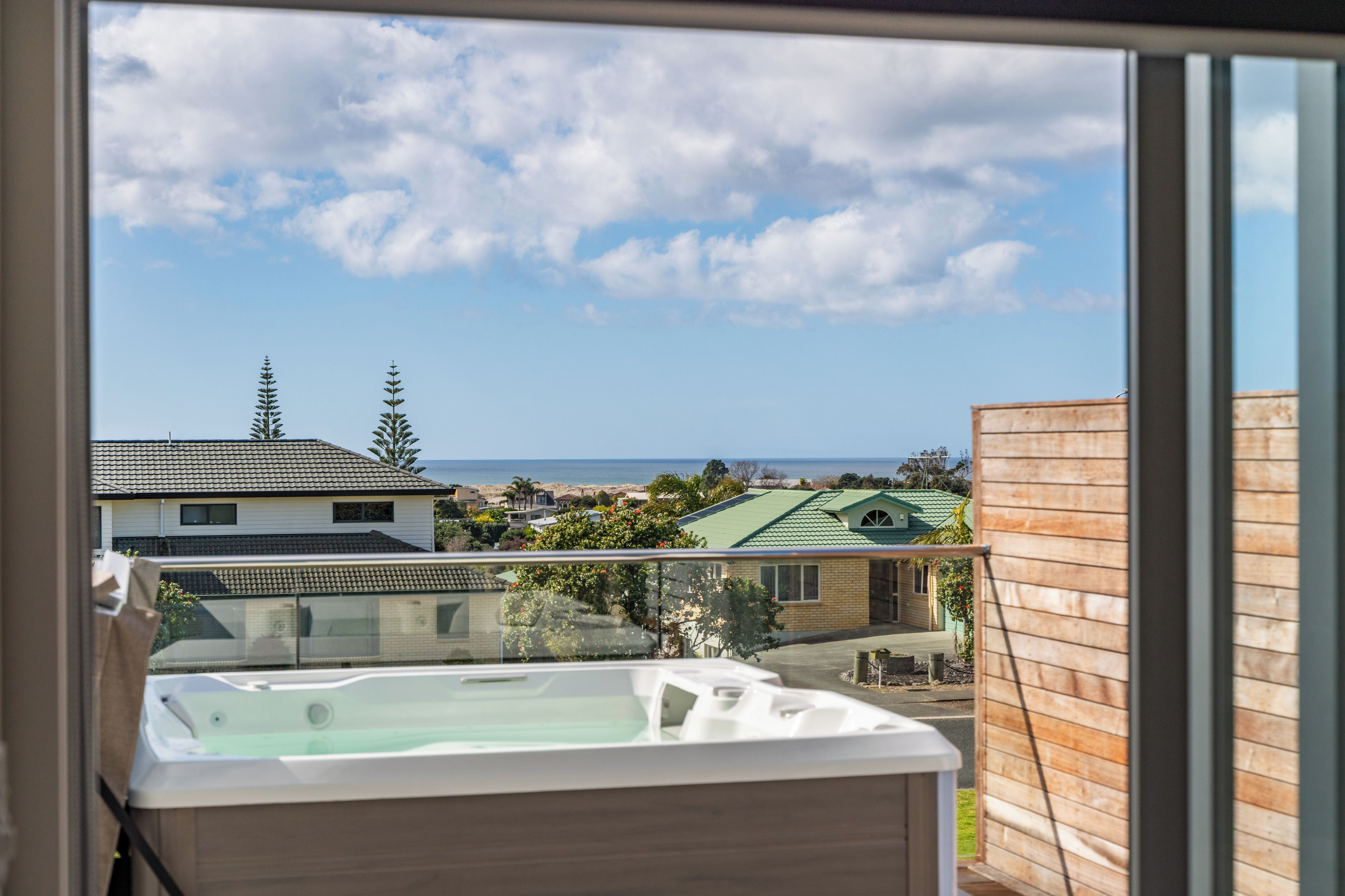 A balcony with a view of a residential area, a body of water, and a clear sky.