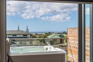 A balcony with a view of a residential area, a body of water, and a clear sky. - Starling - Mangawhai Heads Holiday Home (Mangawhai)