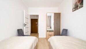 A bedroom with two beds, a wooden door, and a mirror. - Wrocław Three-Bedroom Apt — Parking, A/C & Balcony (Wrocław)