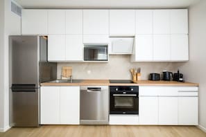 A modern kitchen with white cabinetry, stainless steel appliances, and a wooden countertop.