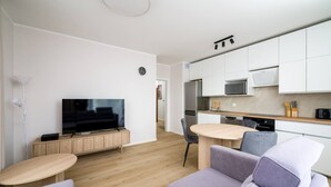 A modern apartment with a living area, a dining table, a kitchen, and a flat-screen TV. - Wrocław Three-Bedroom Apt — Parking, A/C & Balcony (Wrocław)