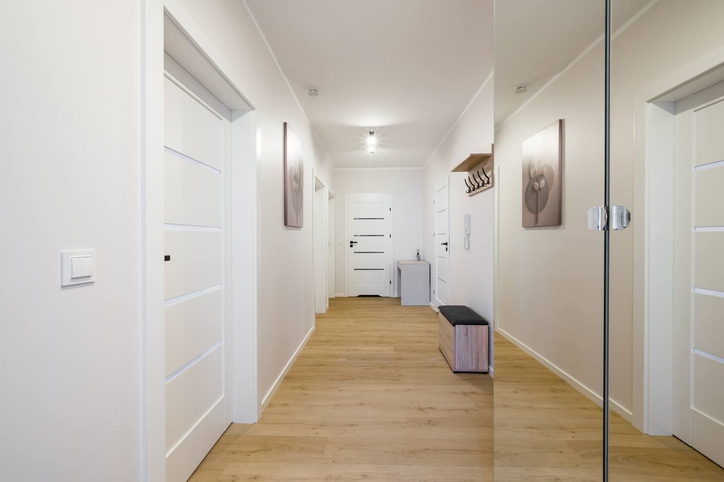 Un couloir aux murs blancs, doté d’un plancher en bois et de portes donnant accès aux différentes pièces.