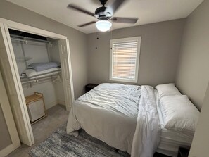 A bedroom with a bed, a ceiling fan, a window with blinds, and a walk-in closet. - Razorback Retreat with Bunks & Game Room (Farmington)