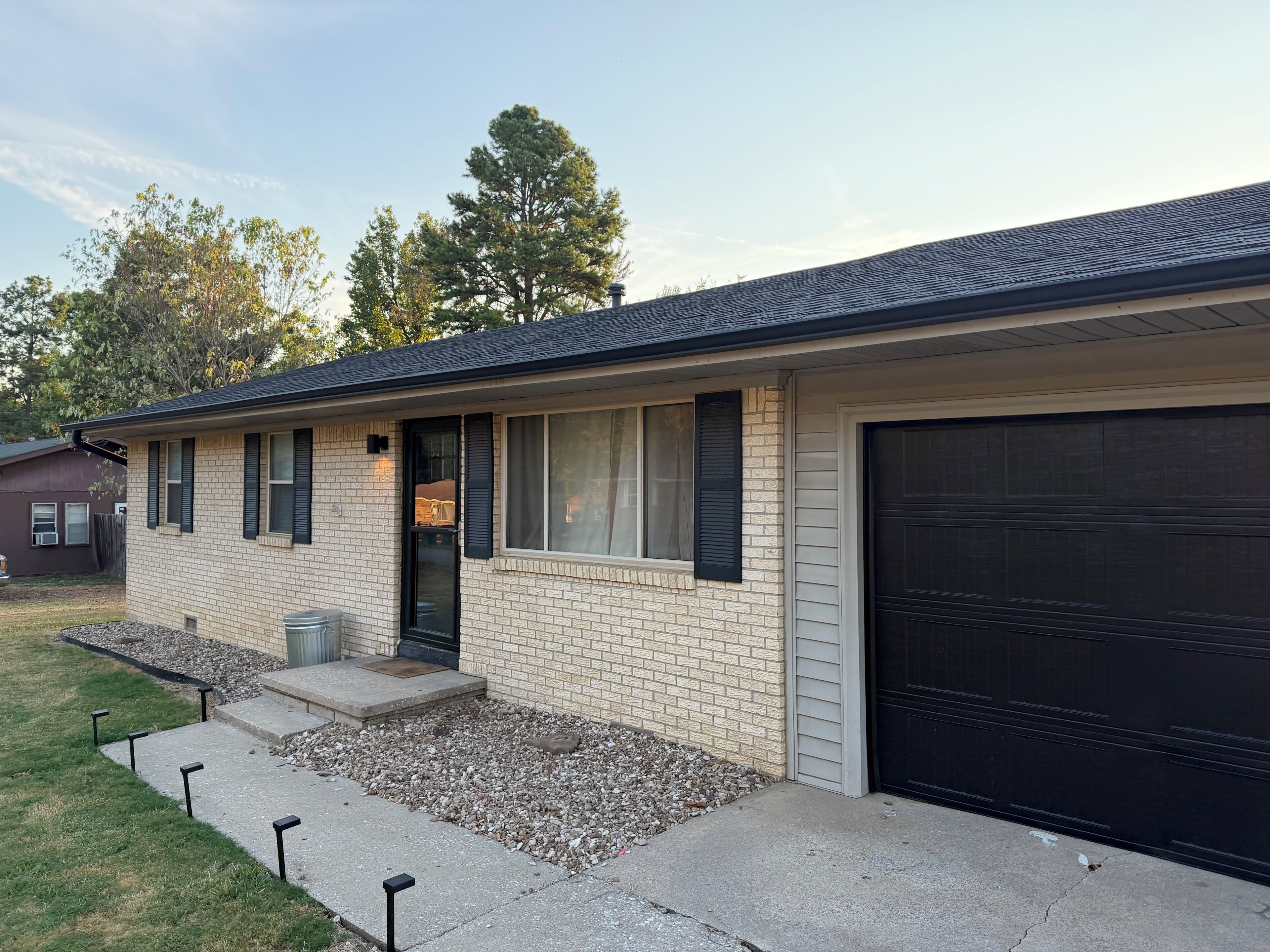 A residential house with a garage, a front door, and a small front yard with a gravel area.