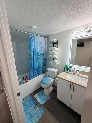 Ein Badezimmer mit Toilette, Waschbecken, Spiegel und einer Duschkabine mit Weltkarten-Motiv.