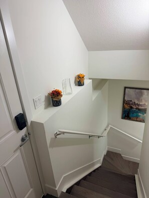 Eine Treppe mit Handlauf, eine Tür mit Schlüsselkartenleser und ein an der Wand hängendes Bild.