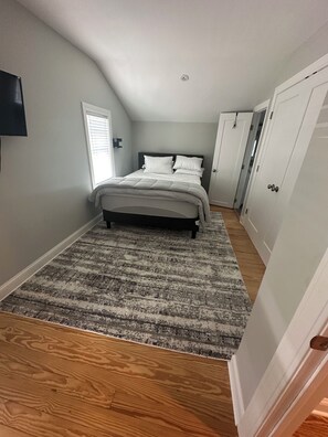 A bedroom with a bed, a window, a door, and a closet. -  3 BR apartment with central AC in the village. Steps to Main St. (Westhampton Beach)