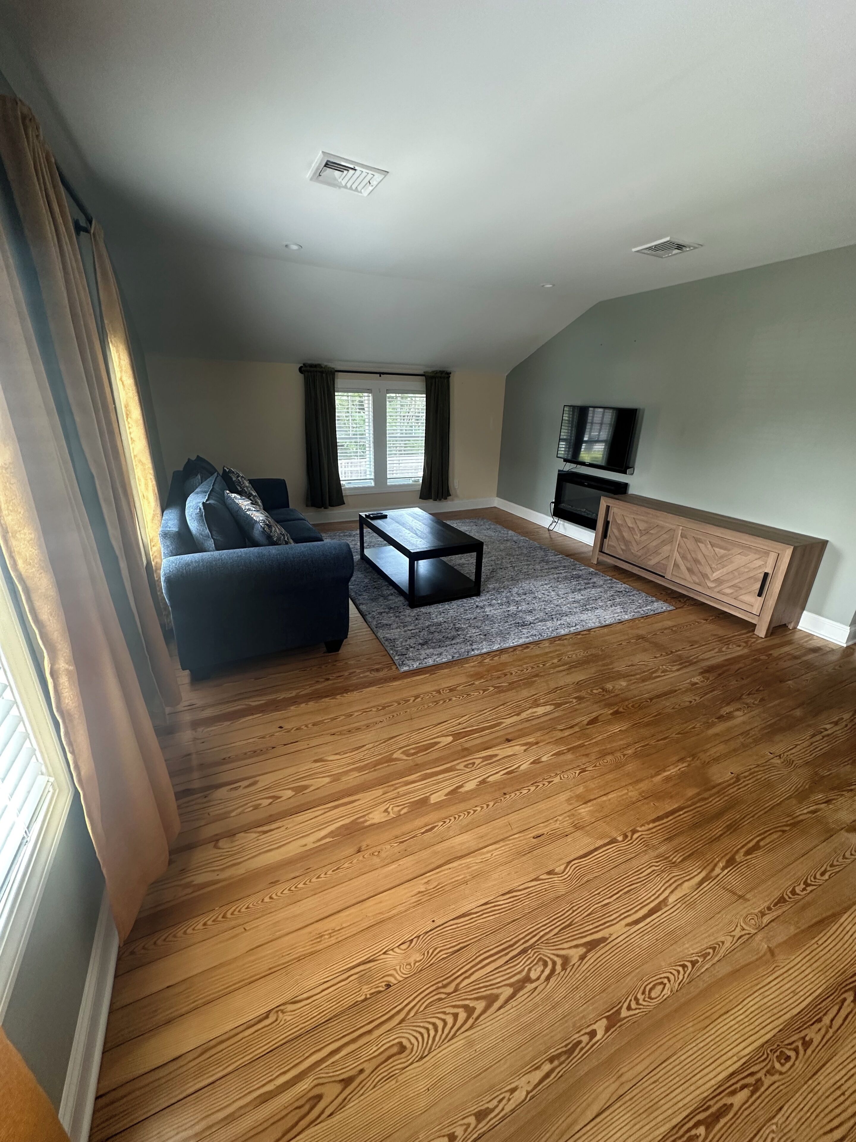 A spacious living room with a sofa, coffee table, and entertainment unit.