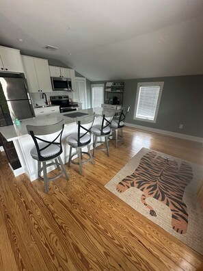 A modern kitchen with white cabinets, stainless steel appliances, and a central island with bar stools. -  3 BR apartment with central AC in the village. Steps to Main St. (Westhampton Beach)