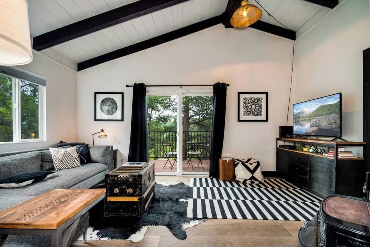 Un salon moderne avec un canapé, une table basse en bois, un téléviseur et un tapis rayé noir et blanc.